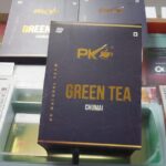 A PK Green Tea Chumai pack from PK Natural Farm appears with bold branding, organic farm tea details, and a 100 gms weight label front and center.